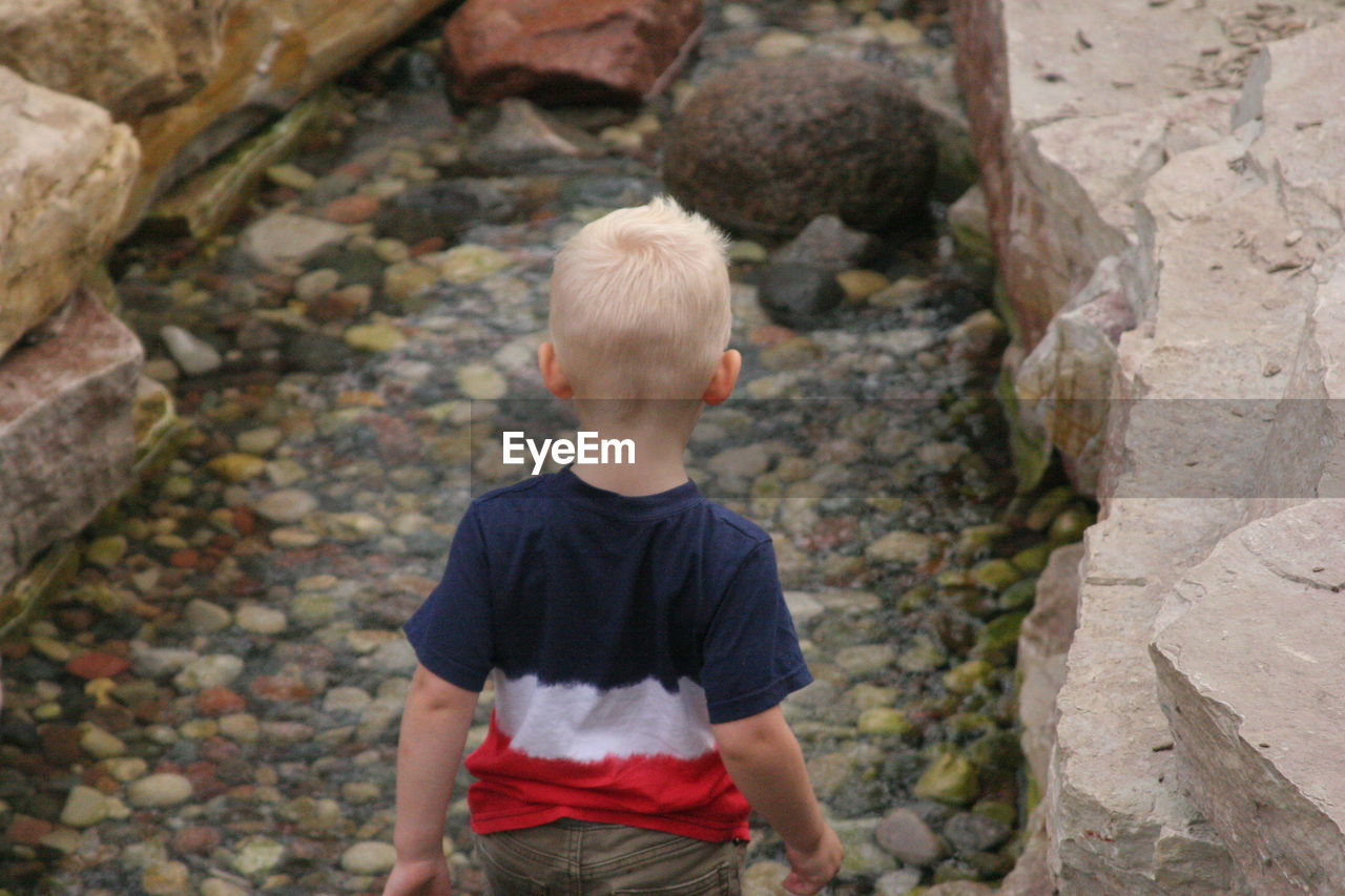 Rear view of boy walking through stream