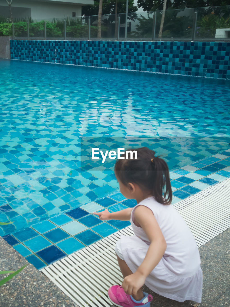 Little asian toddler baby have a fun with a splash near swimming pool