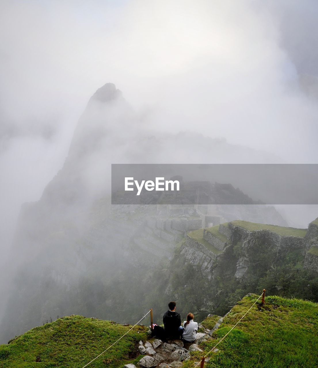 High angle view of couple sitting at the edge of mountain