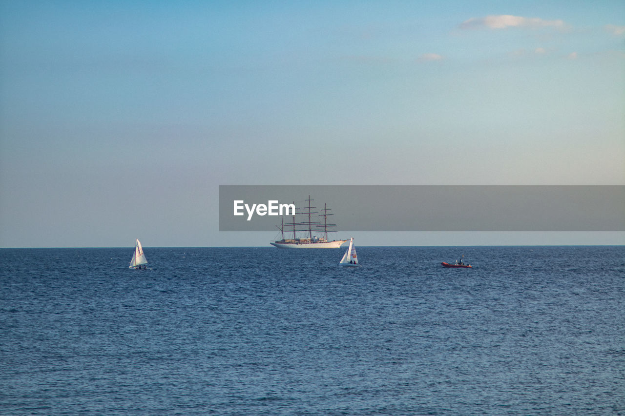 sailboat sailing on sea against sky at sunset