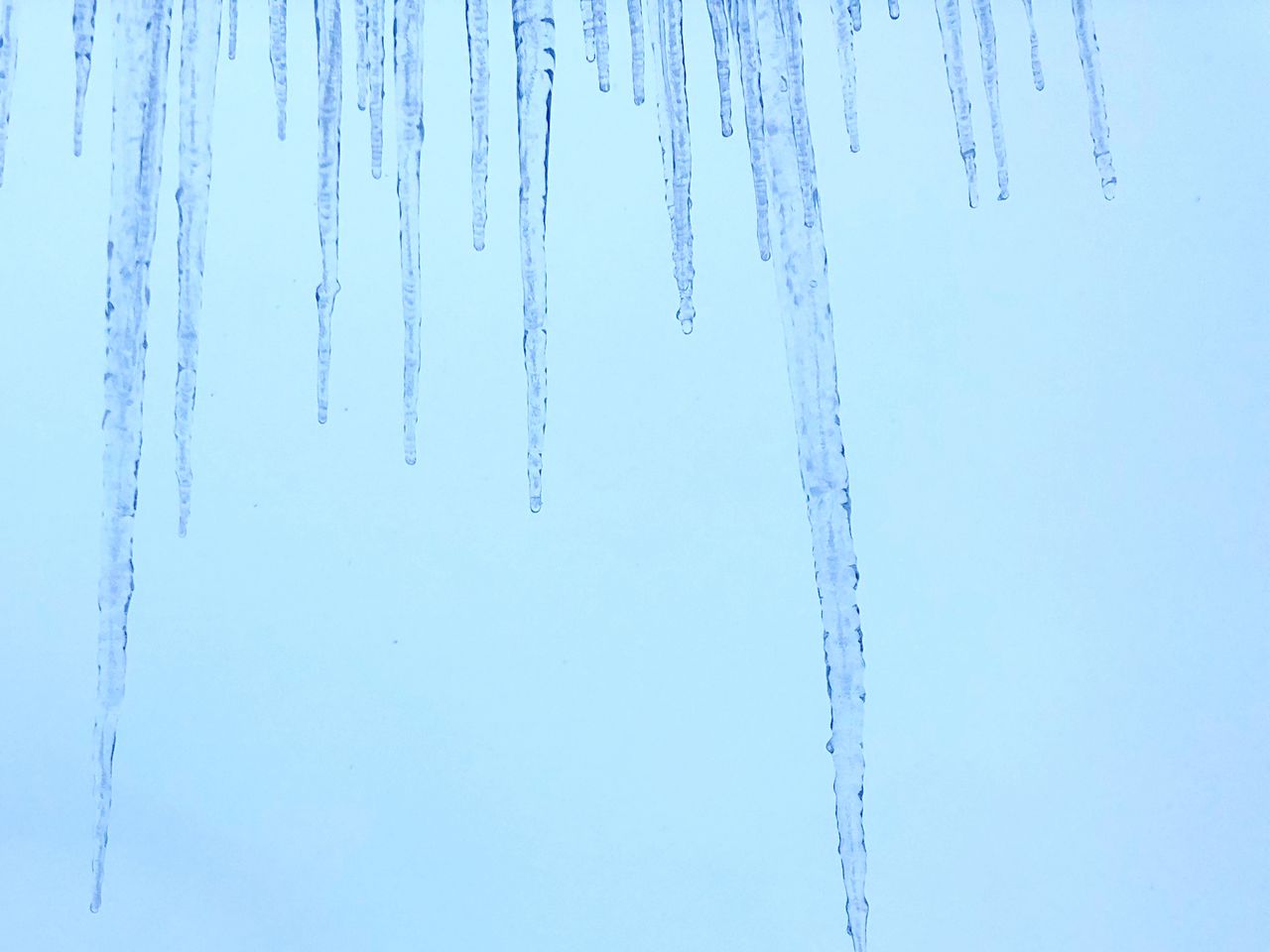 Close-up of icicles against sky during winter