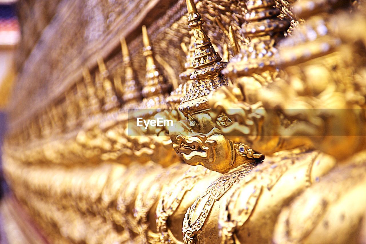 Close-up of golden statues in row outside temple