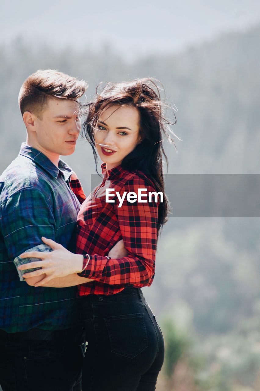 Loving young couple standing in forest