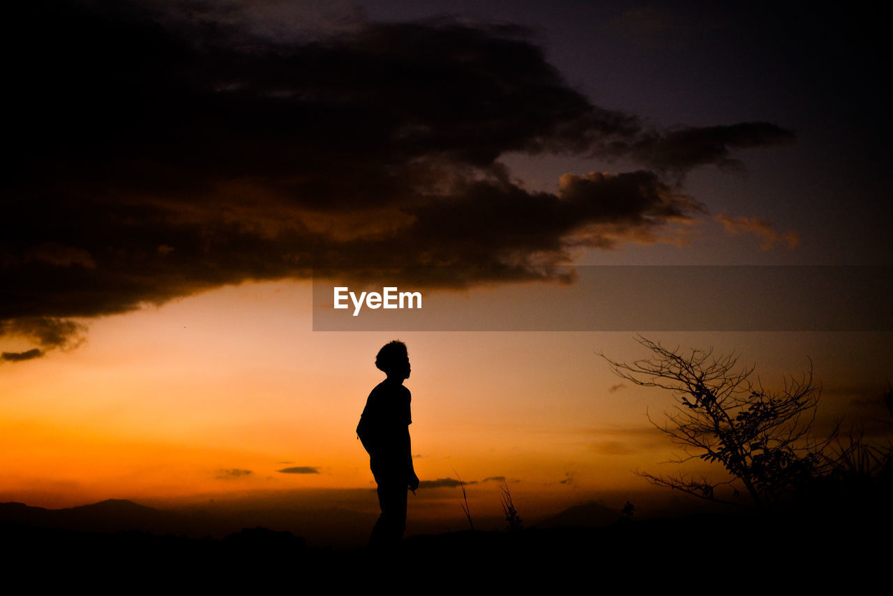 Silhouette man standing on shore against sky during sunset