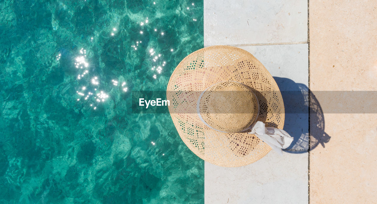 Directly above shot of woman wearing hat sitting by sea