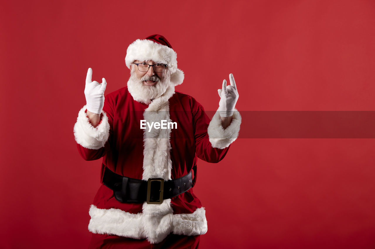 Santa claus making a rocker gesture on a red background