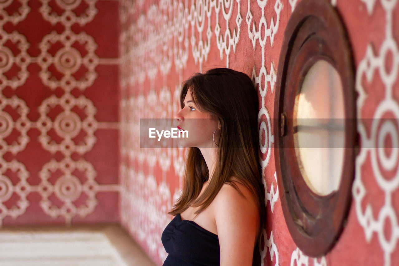 Side view of woman standing by wall