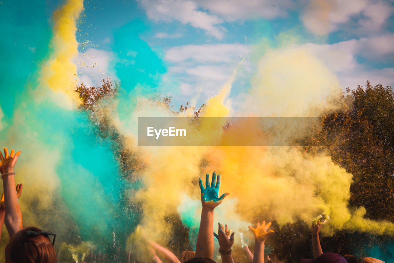 People playing with powder paints against sky