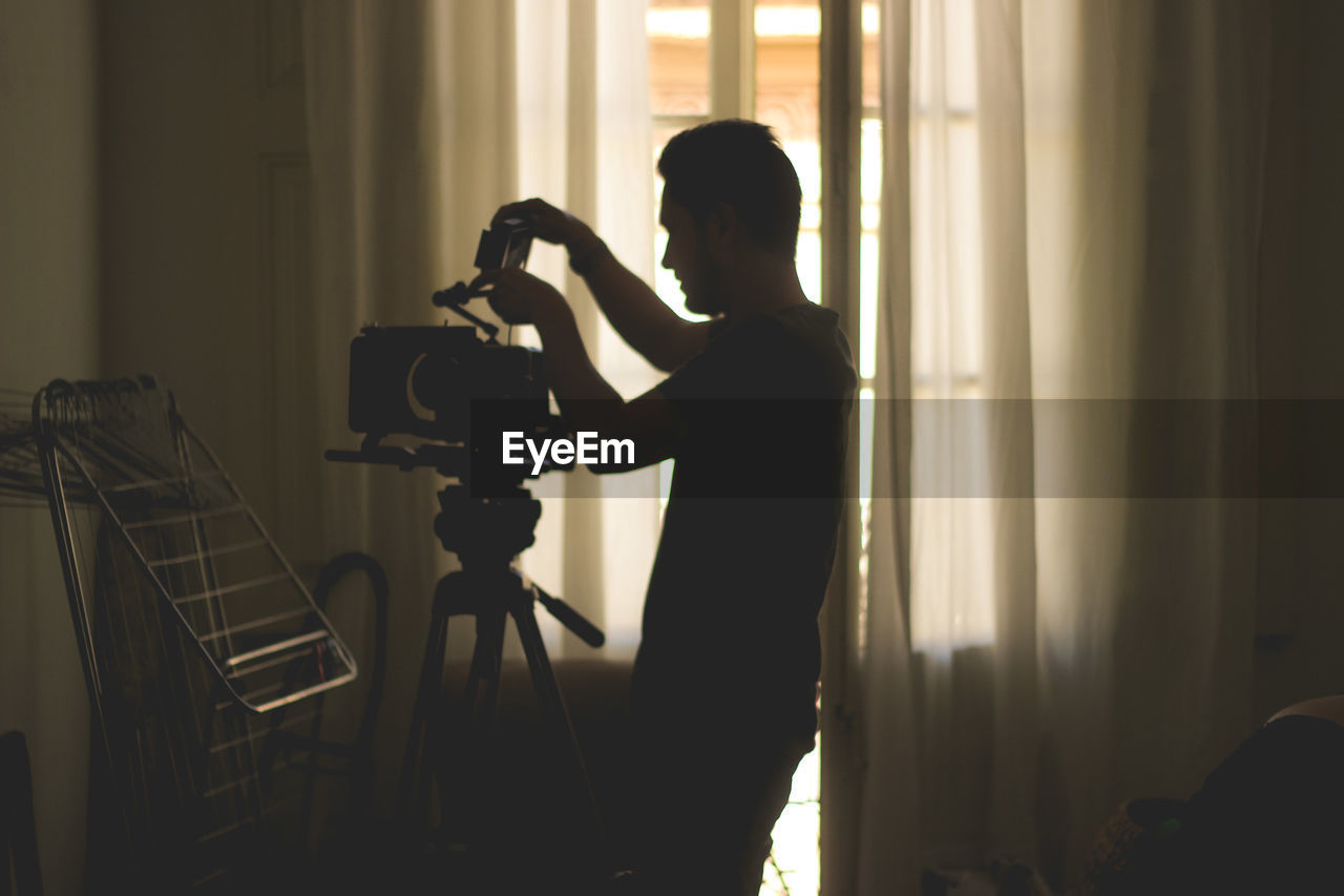 Side view of silhouette man photographing at home