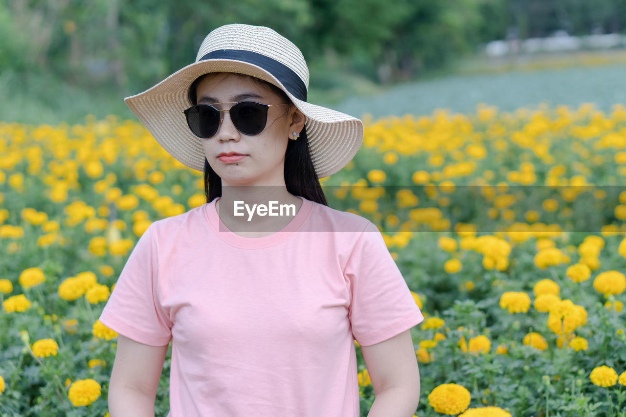 Woman wearing sunglasses while standing by flowering plants