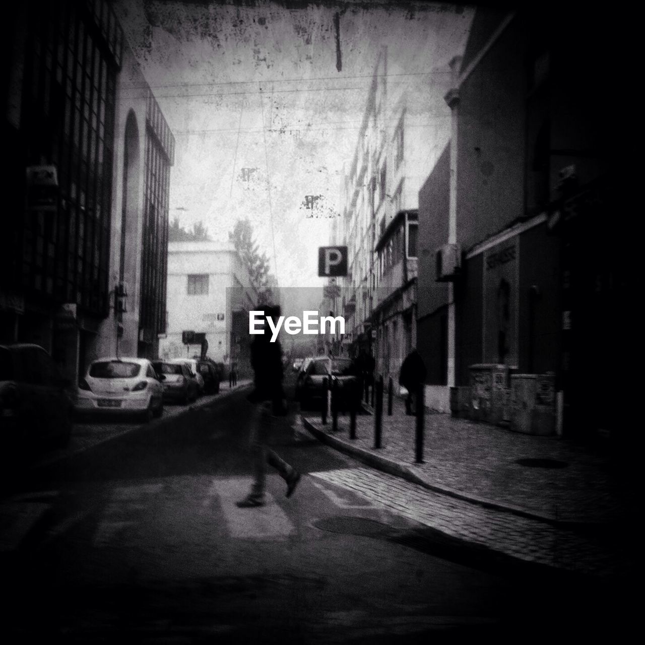 Blurred motion of man walking on street amidst buildings in city