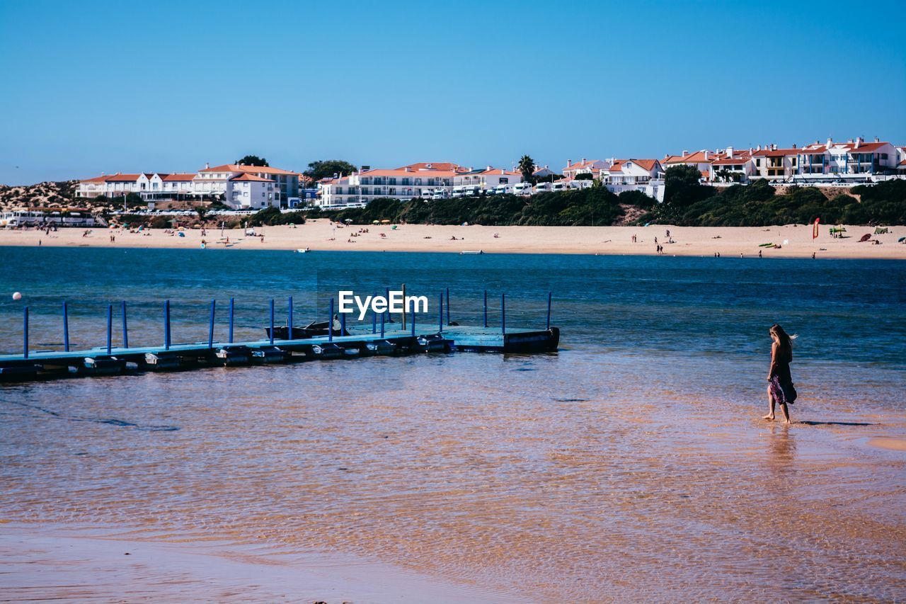 High angle view of woman walking at beach against city