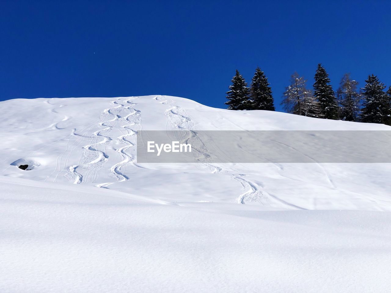 Snow covered landscape against blue sky