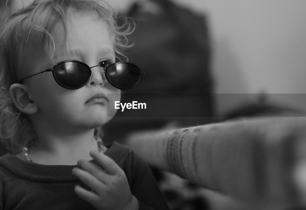 Close-up of cute girl wearing sunglasses at home