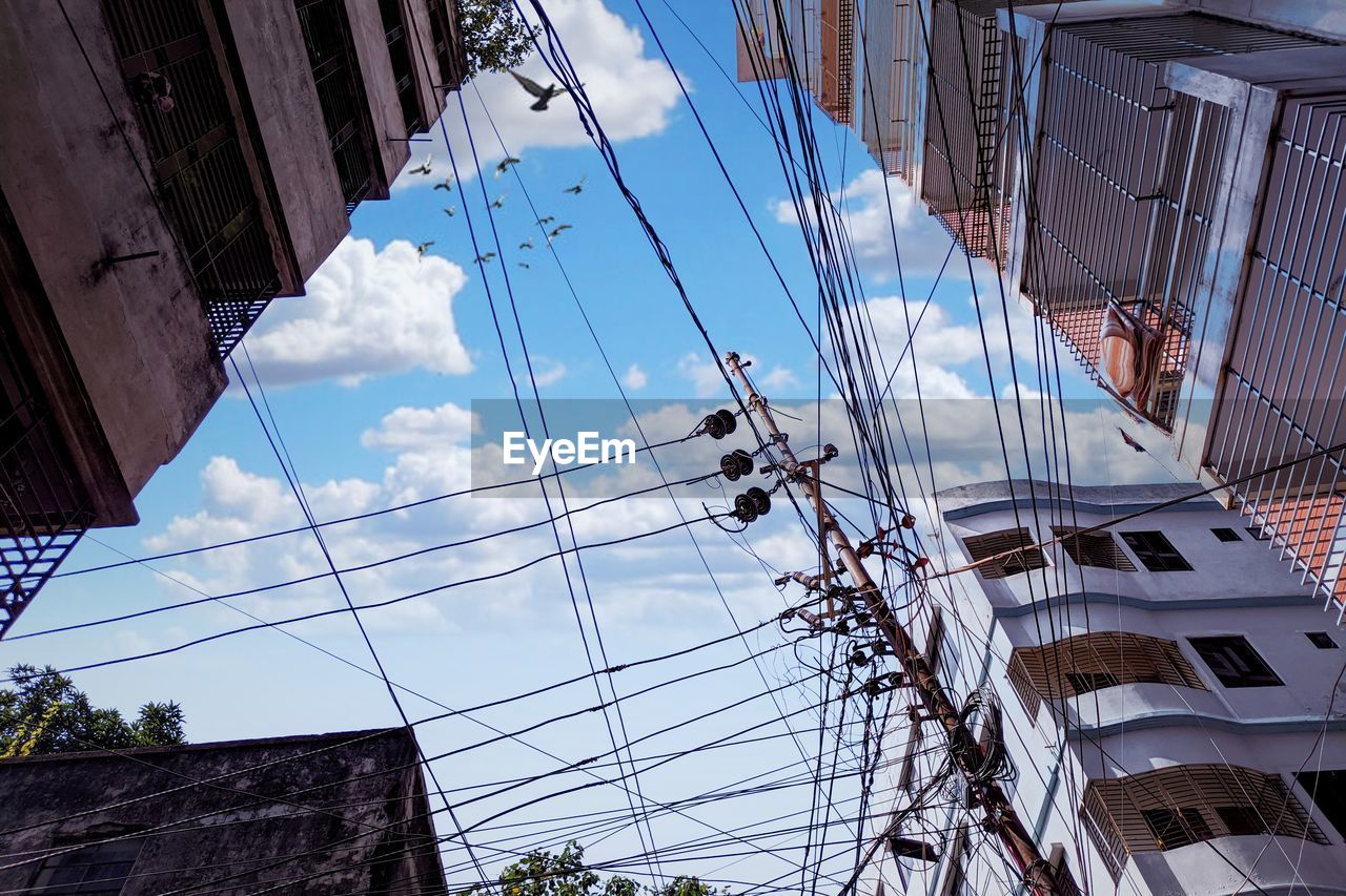 LOW ANGLE VIEW OF CABLES AGAINST BUILDINGS