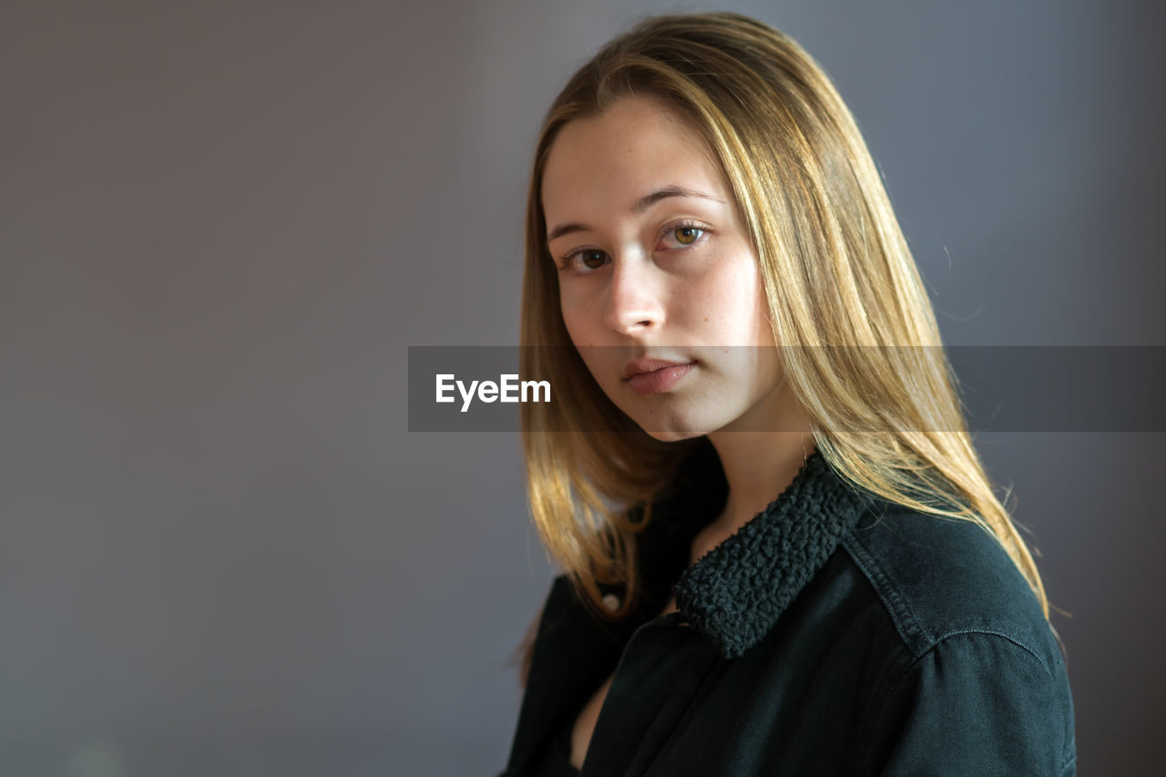 Portrait of beautiful young woman against gray background