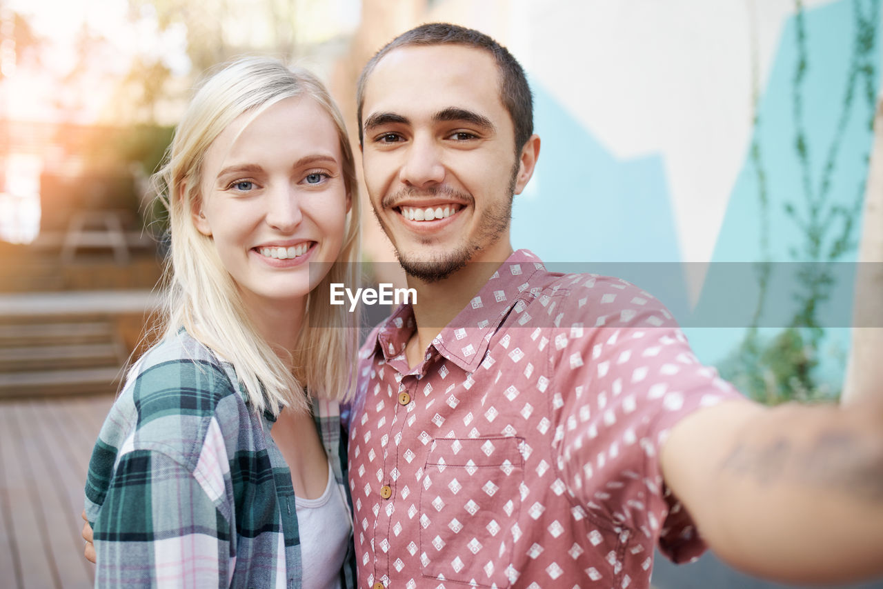 Smiling man taking selfie with girlfriend