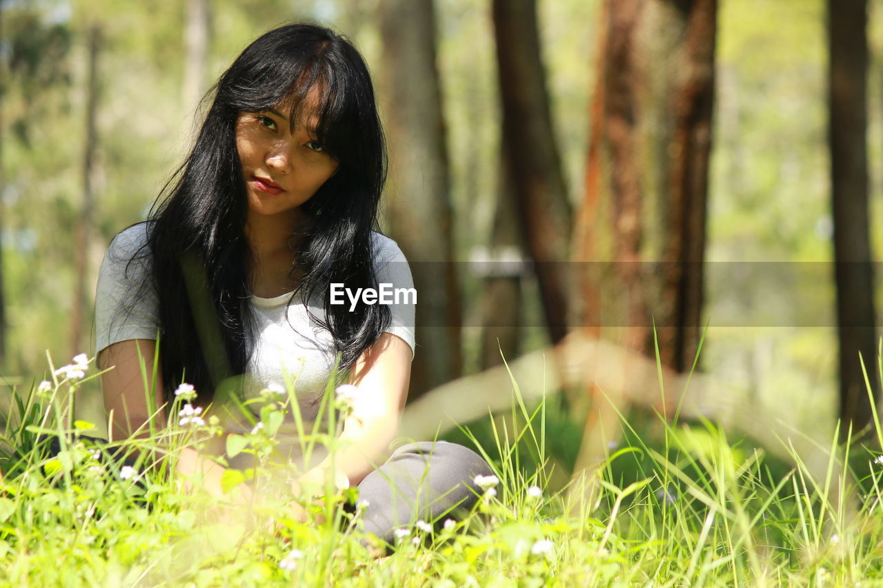 Portrait of young woman sitting on field at park