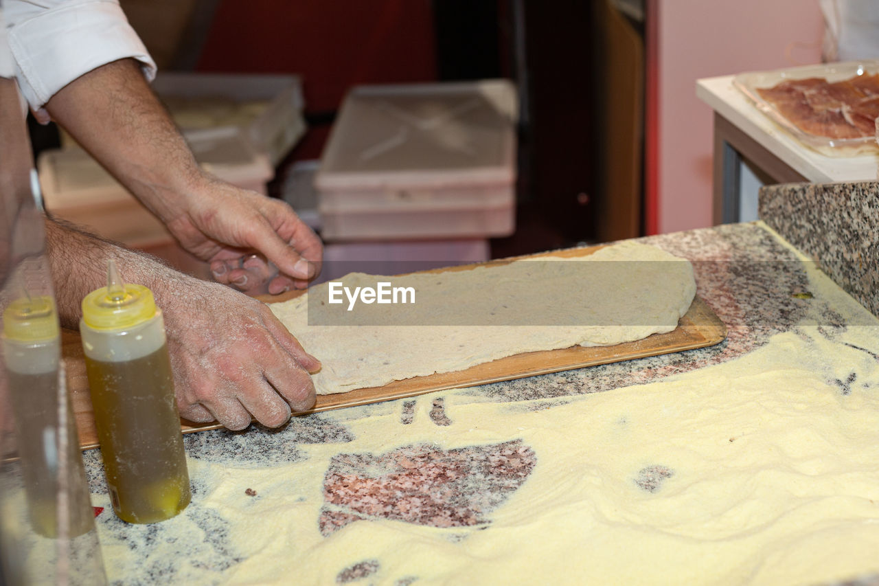 occupation, one person, food and drink, food, hand, baked, indoors, adult, working, business, freshness, dough, men, skill, preparing food, store, business finance and industry, kitchen, making, small business, midsection, bakery, holding, baker