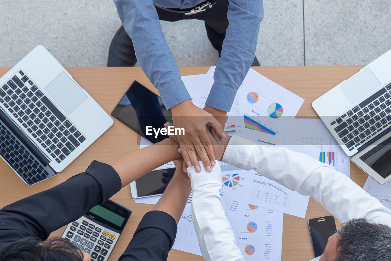 High angle view of colleagues stacking hands in office