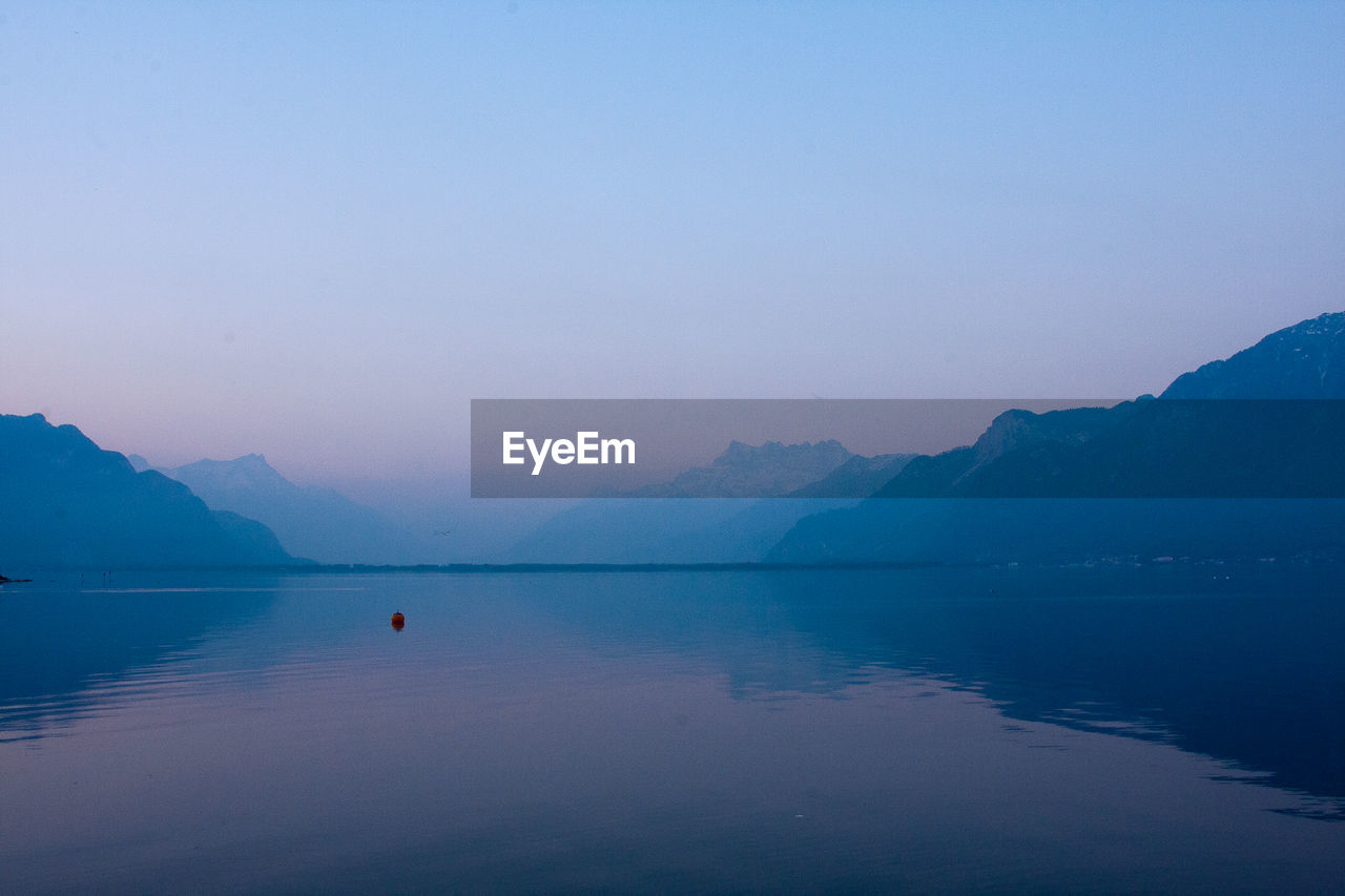 Scenic view of lake by mountains against sky