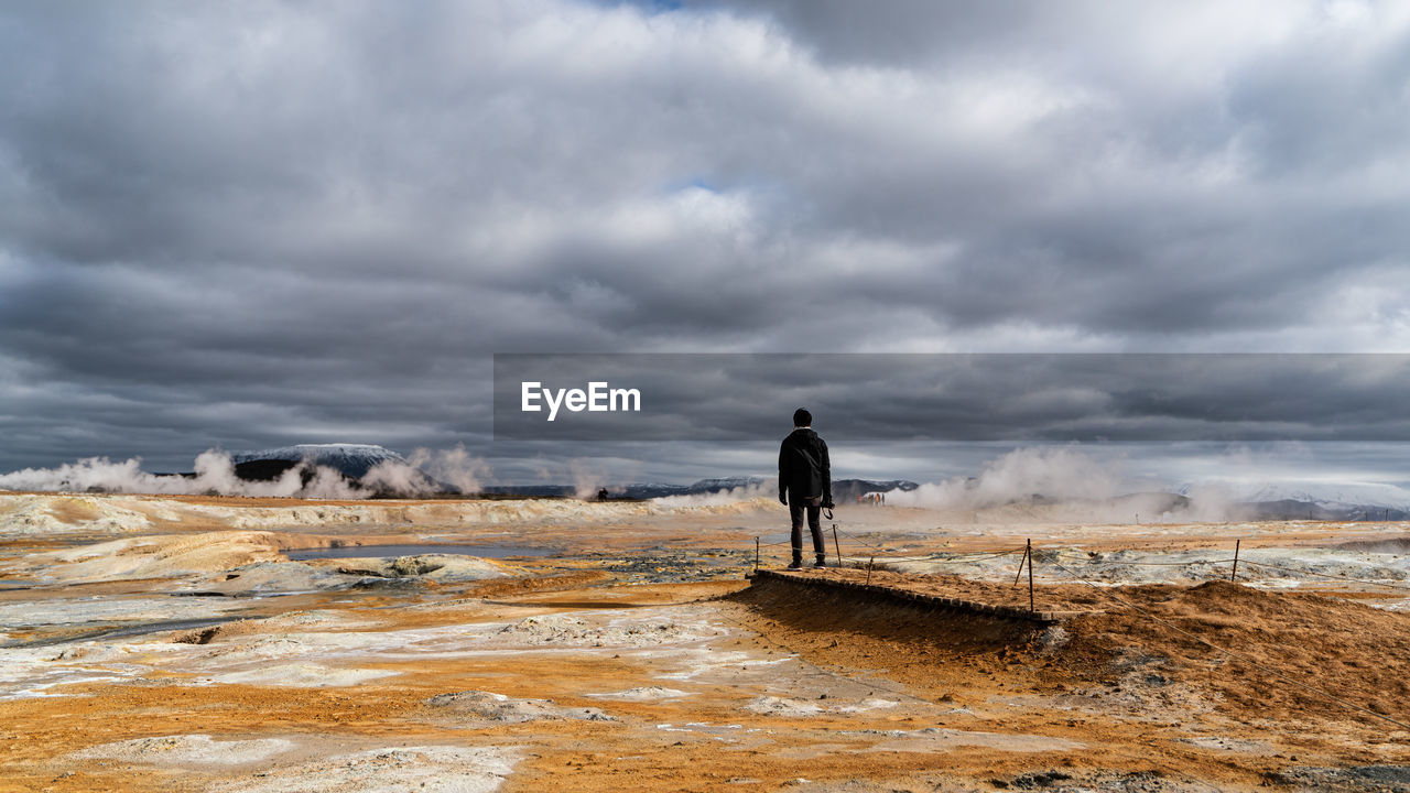 Rear view of man standing on land against sky in hverir, iceland