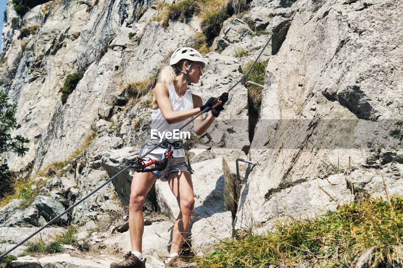 Full length of woman climbing rock