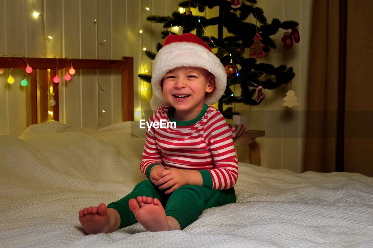 Christmas boy in santa hat smiling at home evening. new year and holidays. christmas happiness. the