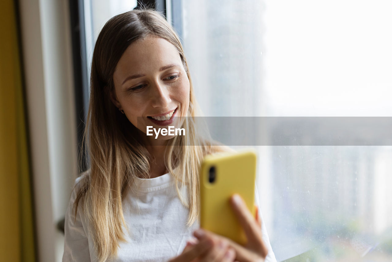 portrait of young woman using mobile phone at home