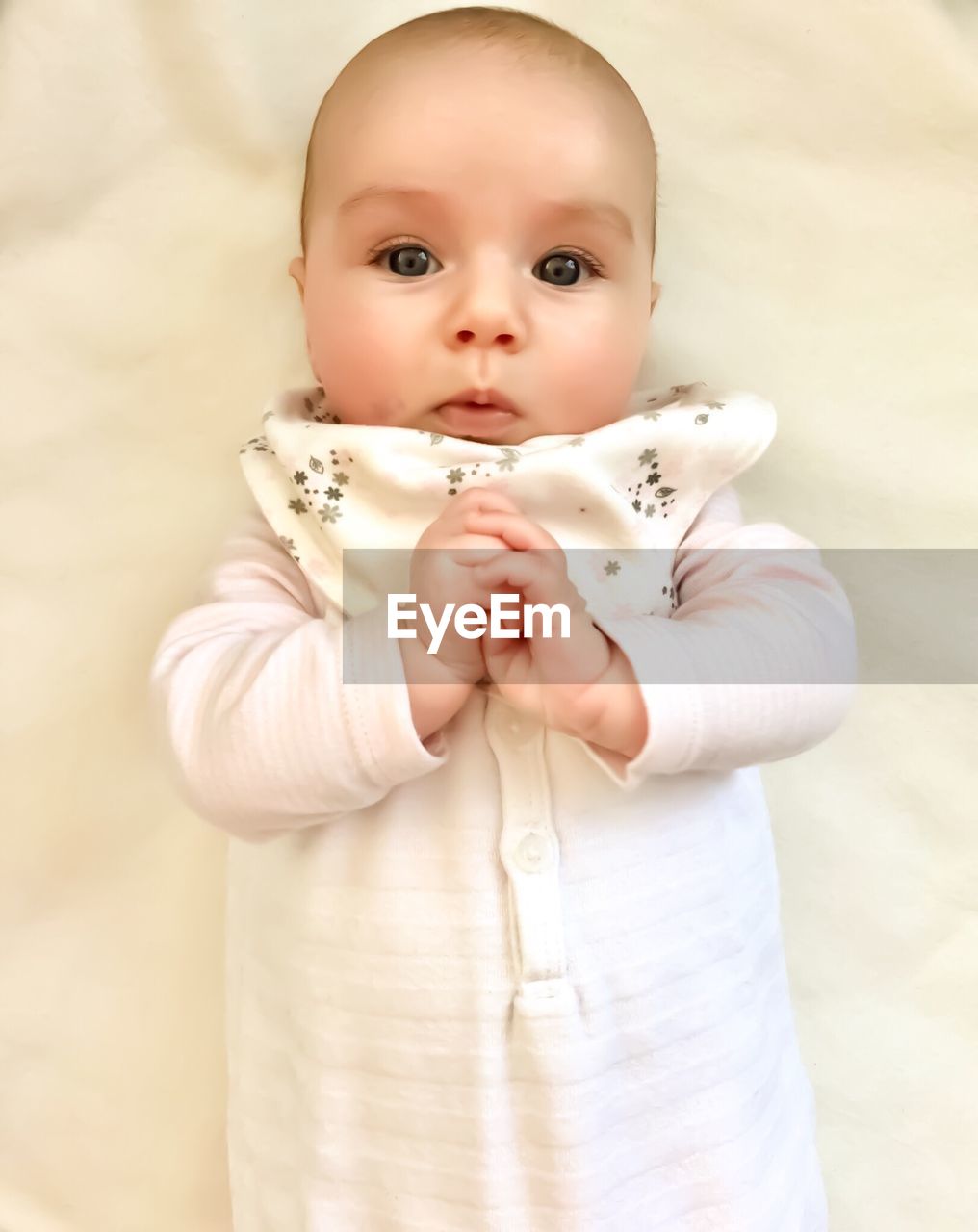 Portrait of cute baby girl lying on bed