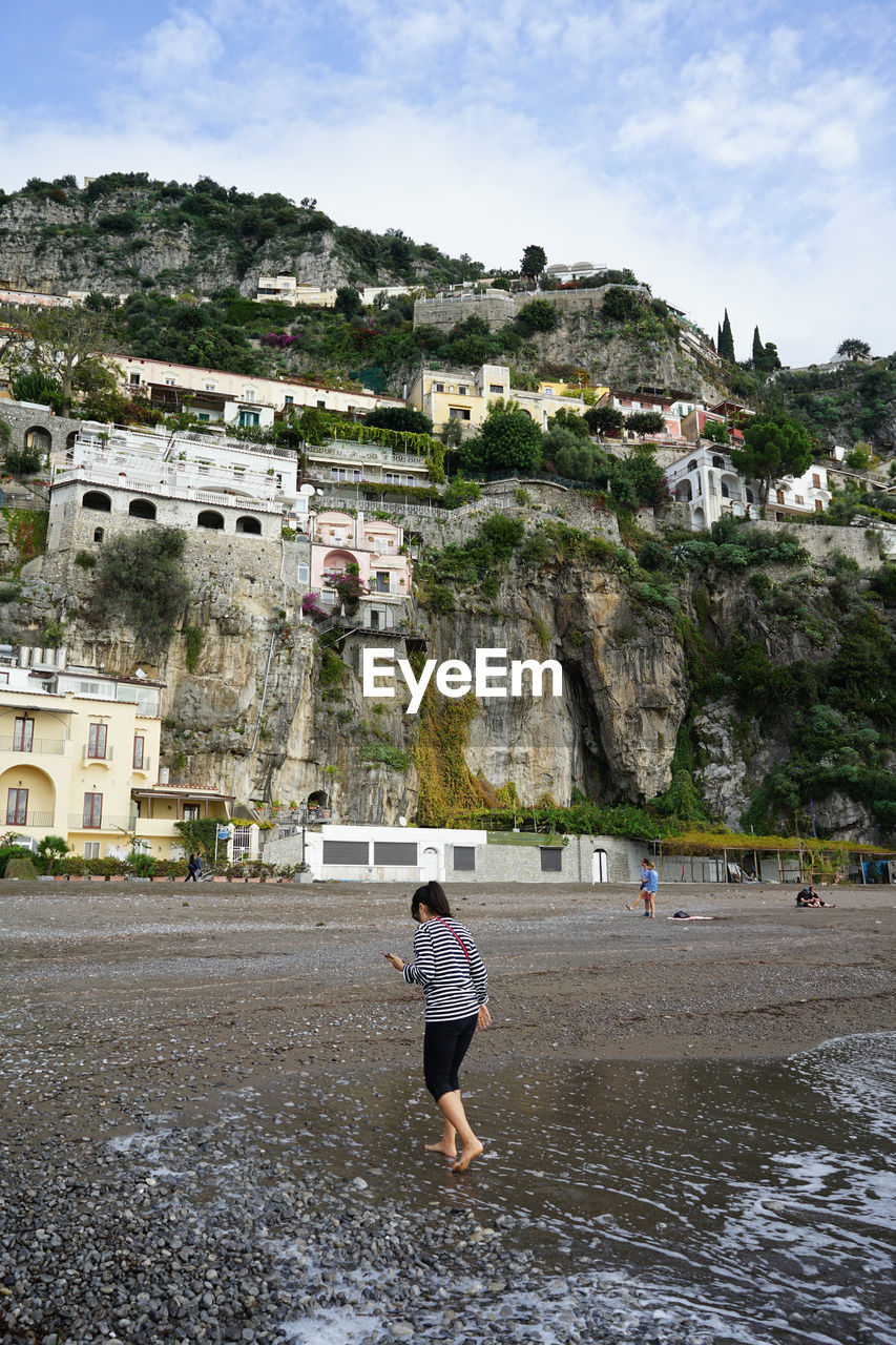 Woman walking on shore at beach against mountain