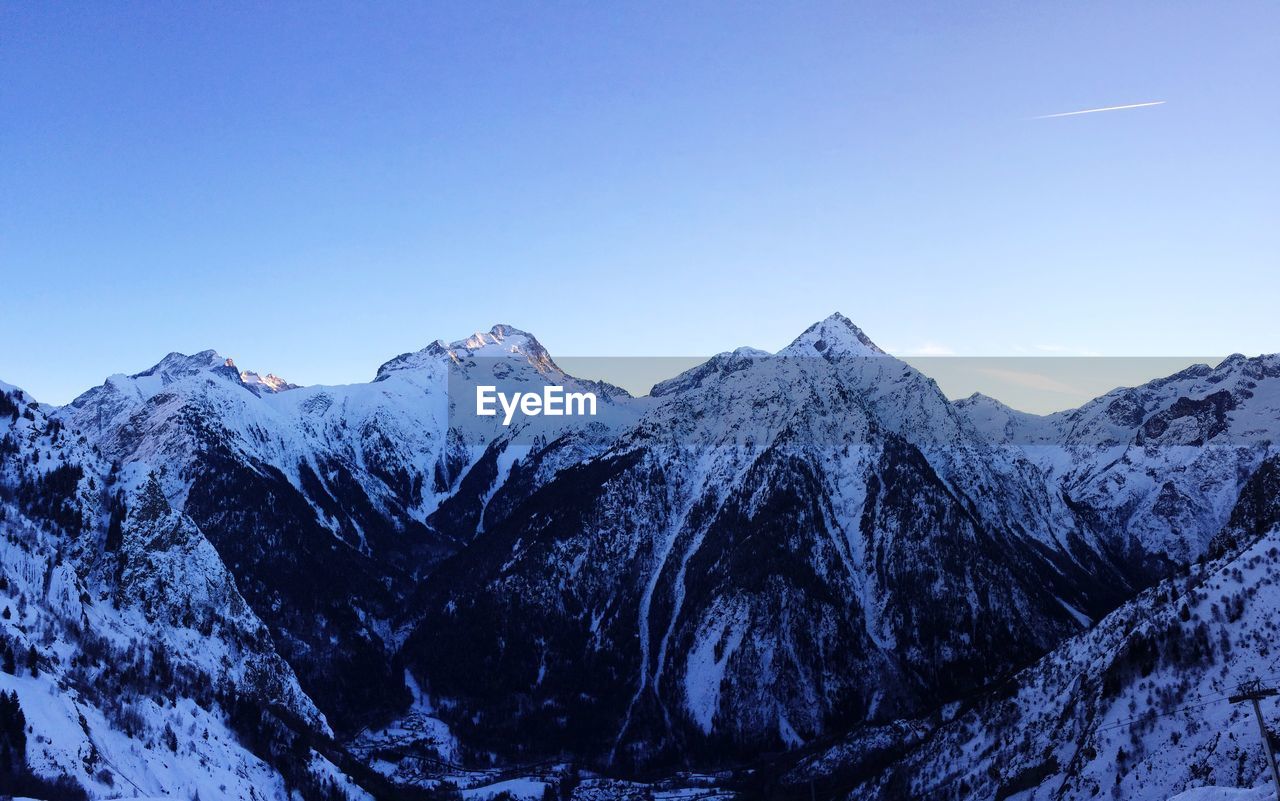 Scenic view of snowcapped mountains against clear blue sky