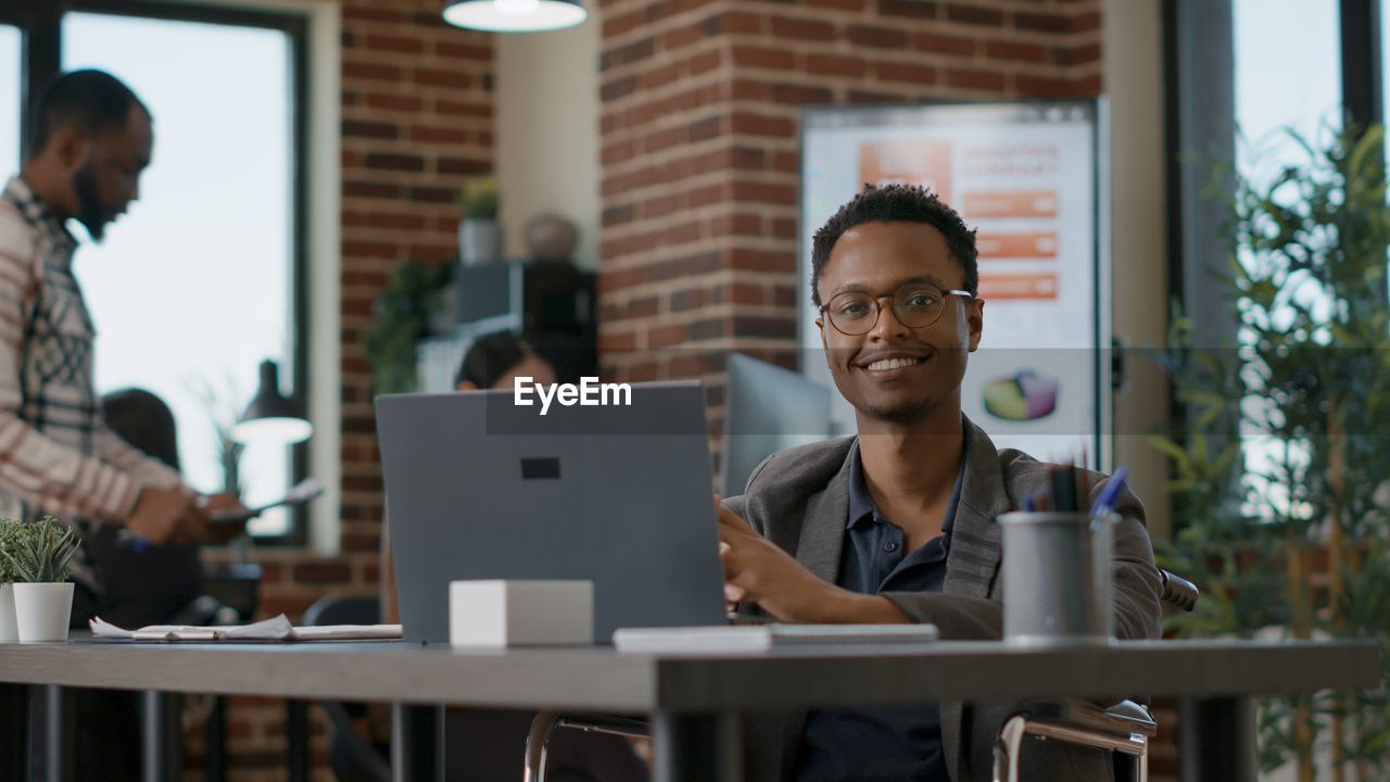 Smiling businessman with laptop at desk