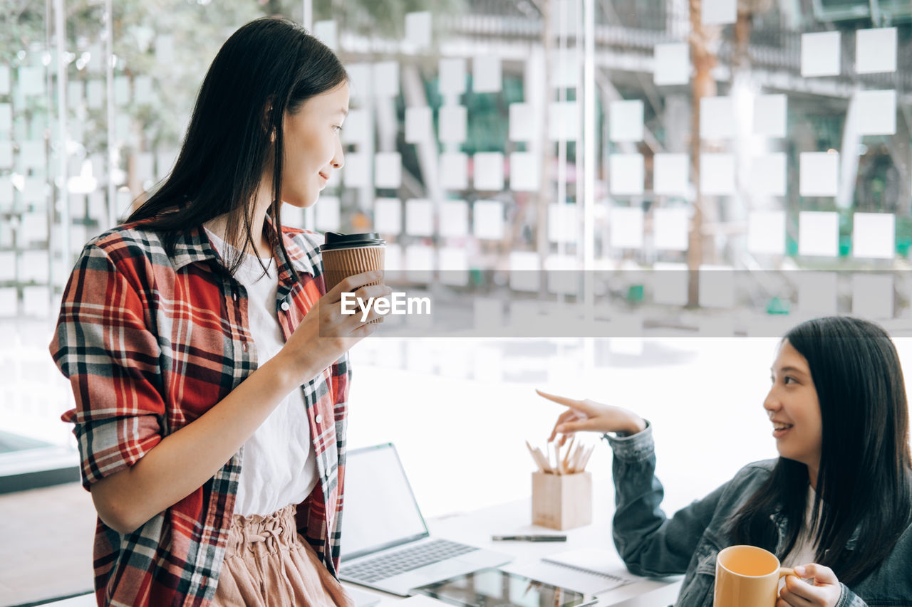 YOUNG WOMAN DRINKING COFFEE CUP AND LAPTOP