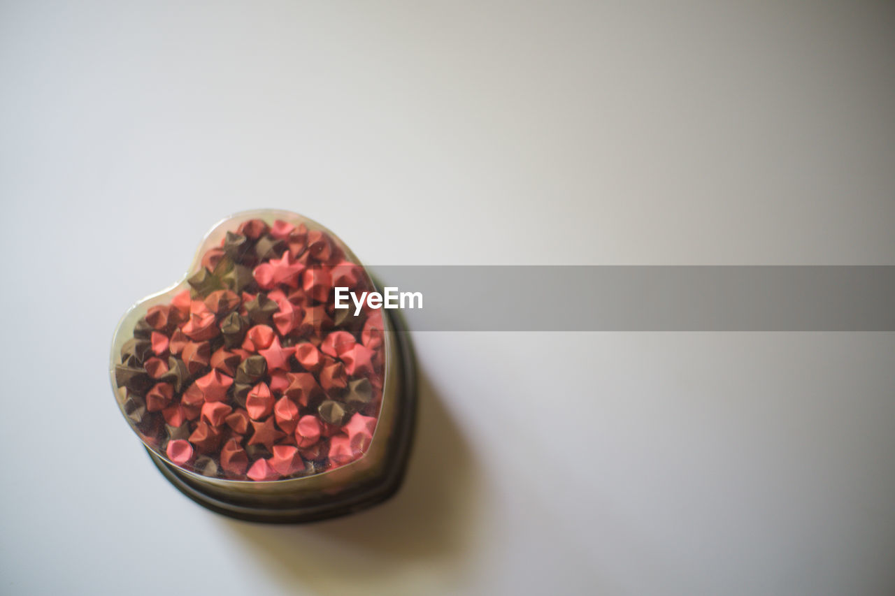 High angle view of candies in heart shape container on table