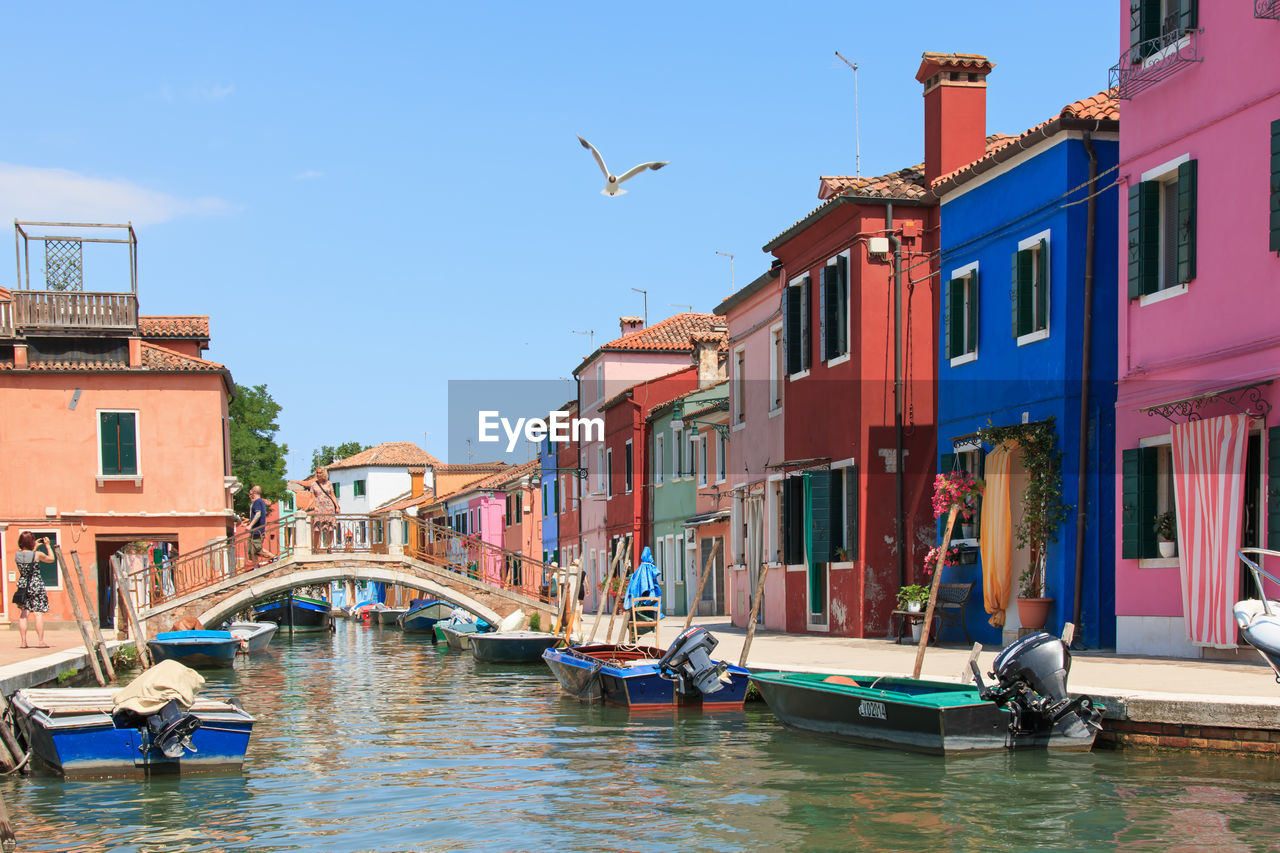 Boats moored on canal by colorful buildings at burano island