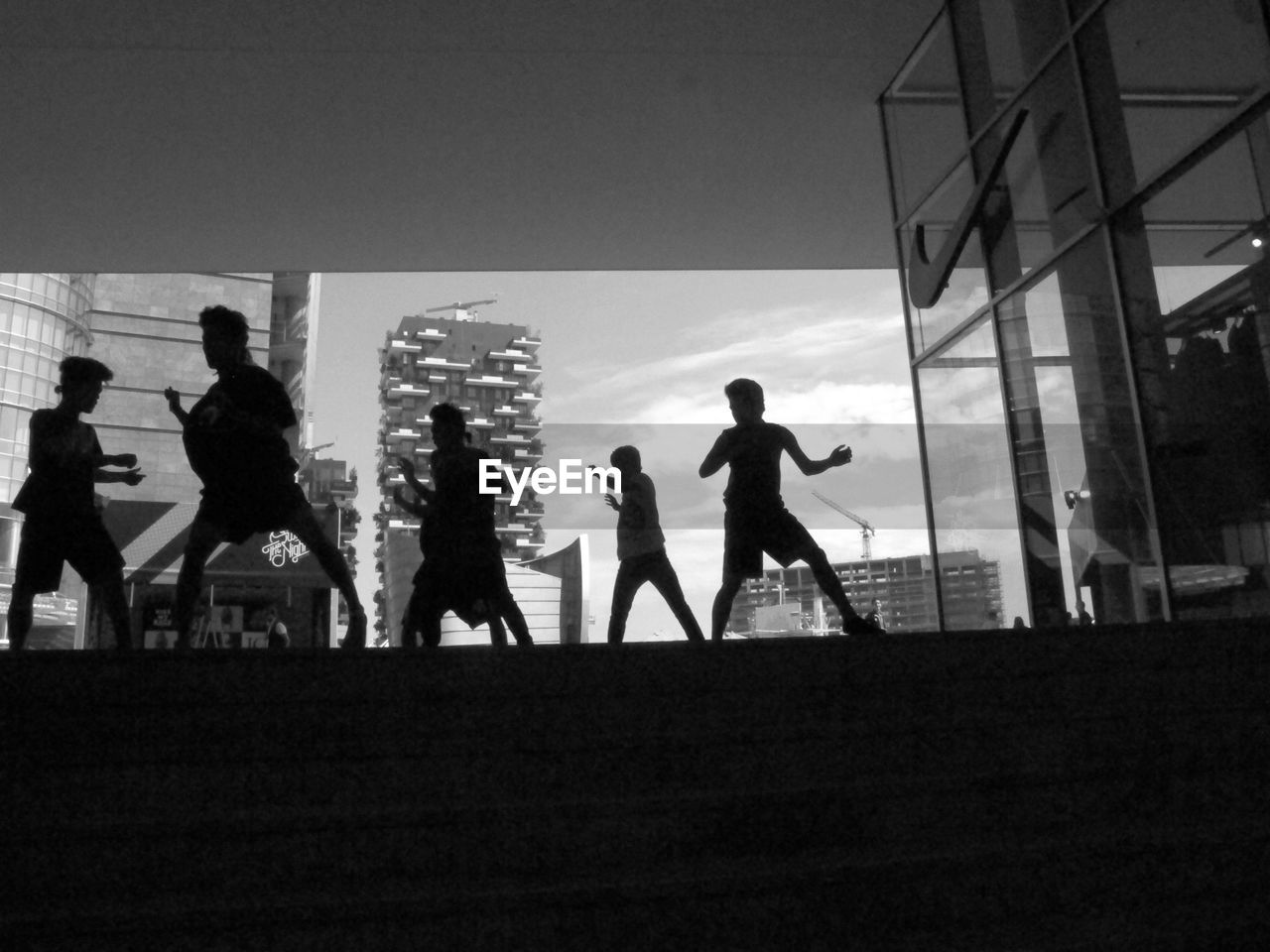 Silhouette boys dancing with buildings in background