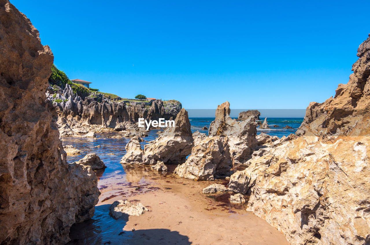 Rocks on beach against clear blue sky