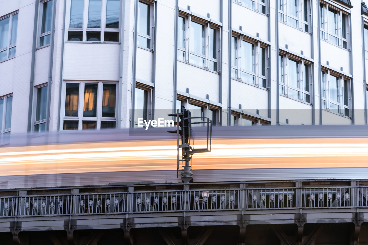 Low angle view of illuminated train moving by building in city