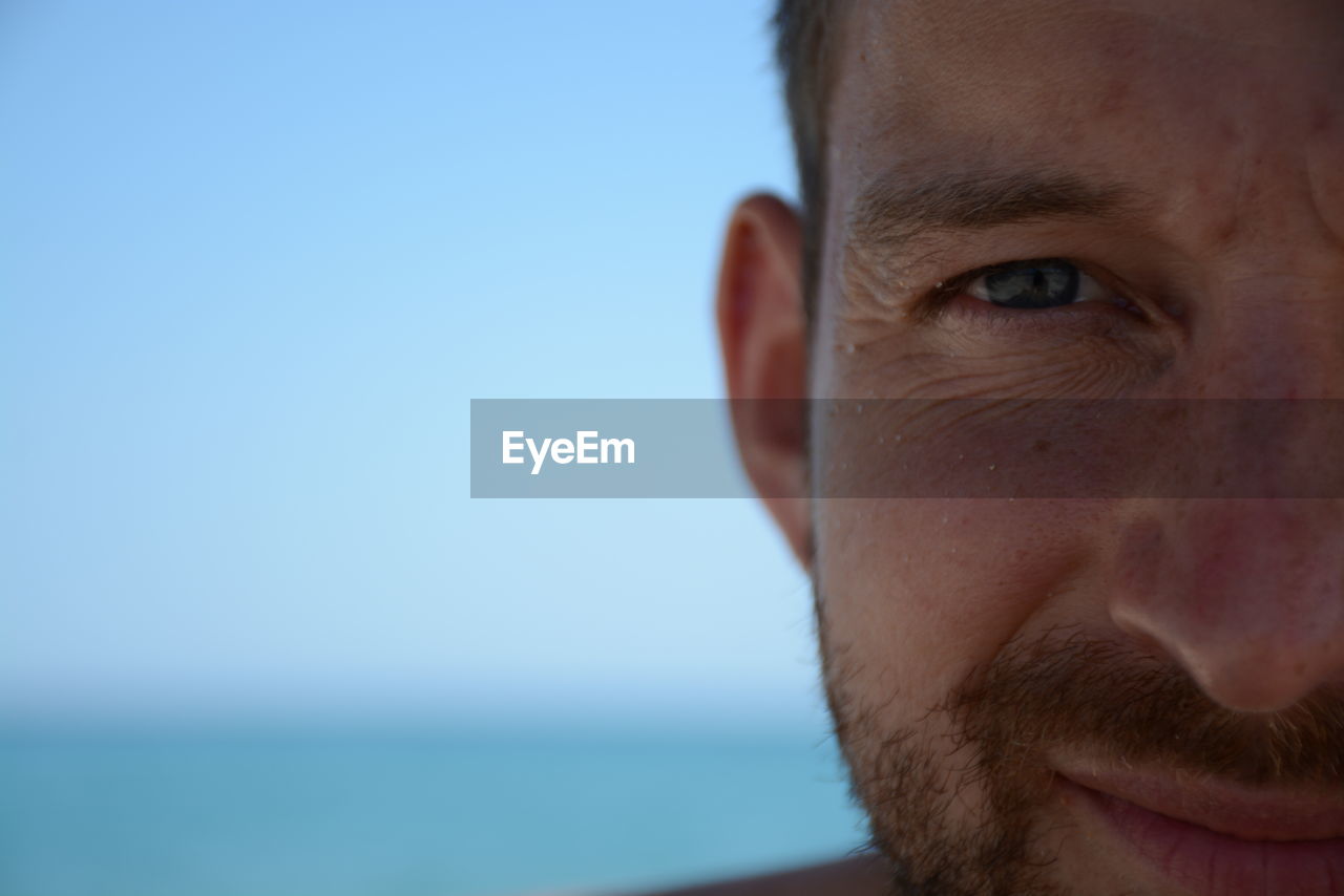 CLOSE-UP PORTRAIT OF MAN AGAINST CLEAR SKY