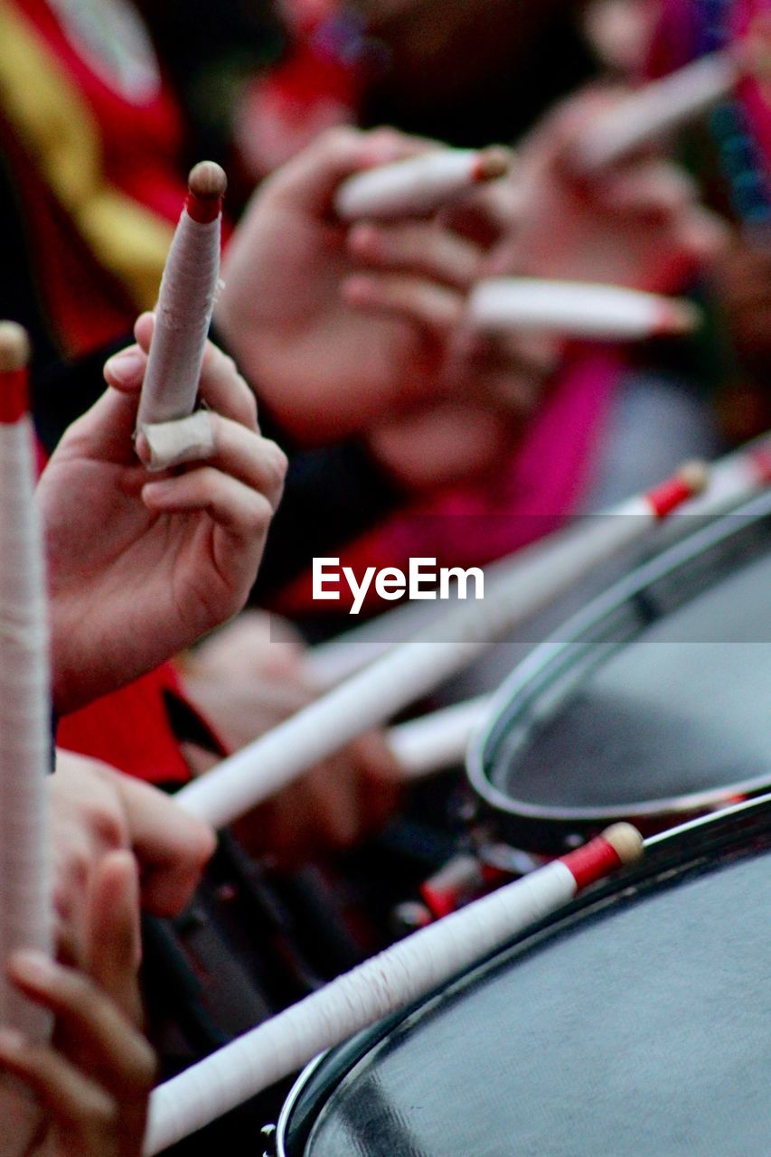 Cropped image of people playing drum with stick