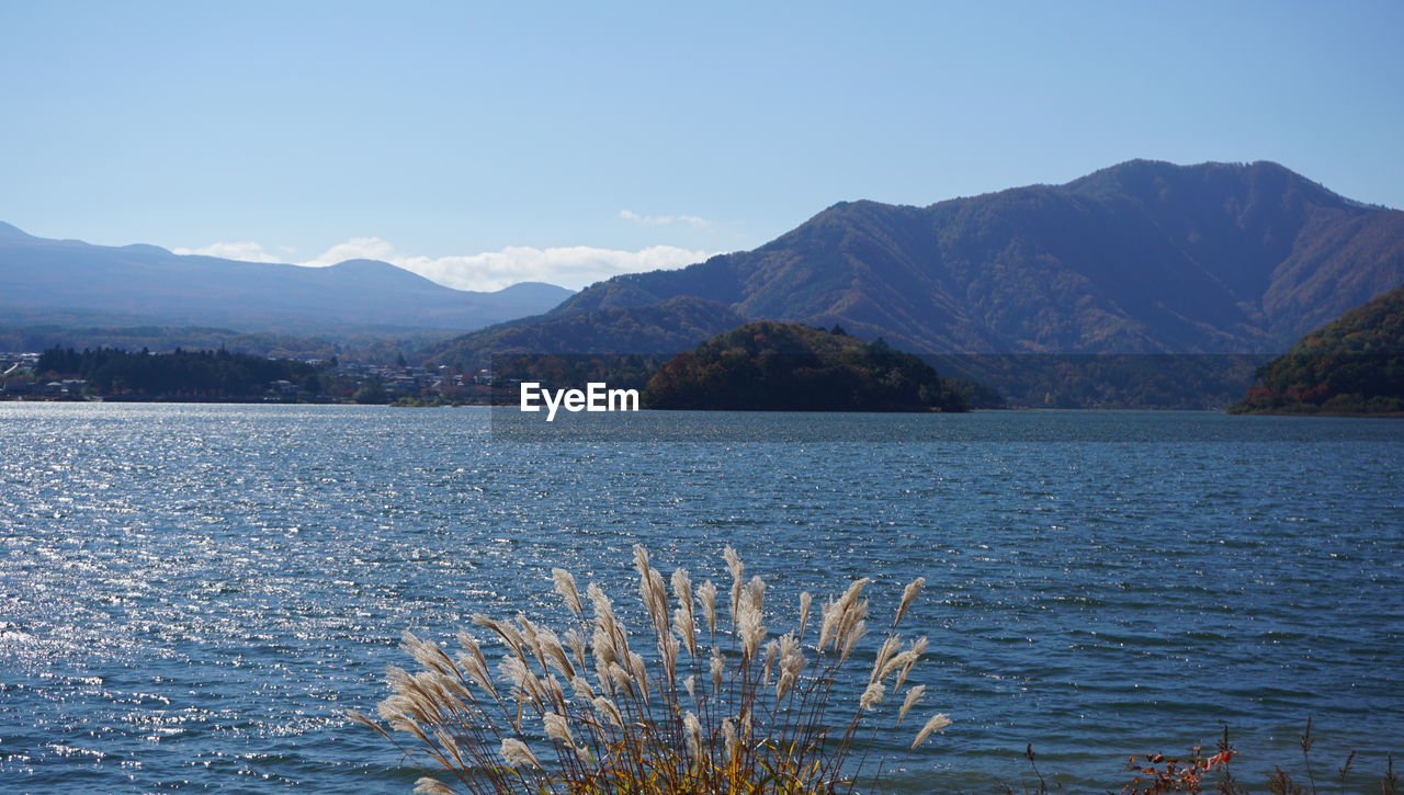 Scenic view of lake and mountains against clear blue sky