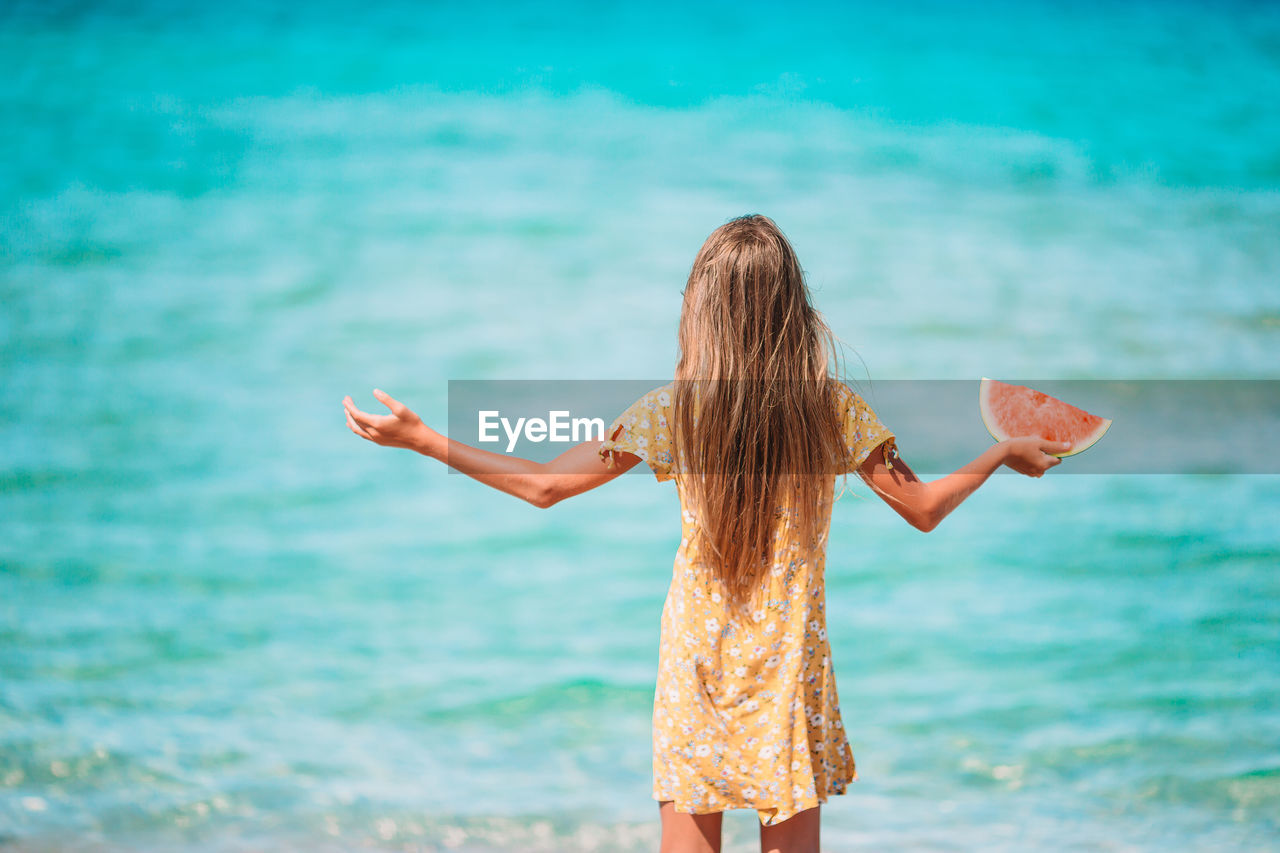 Rear view of woman standing against sea