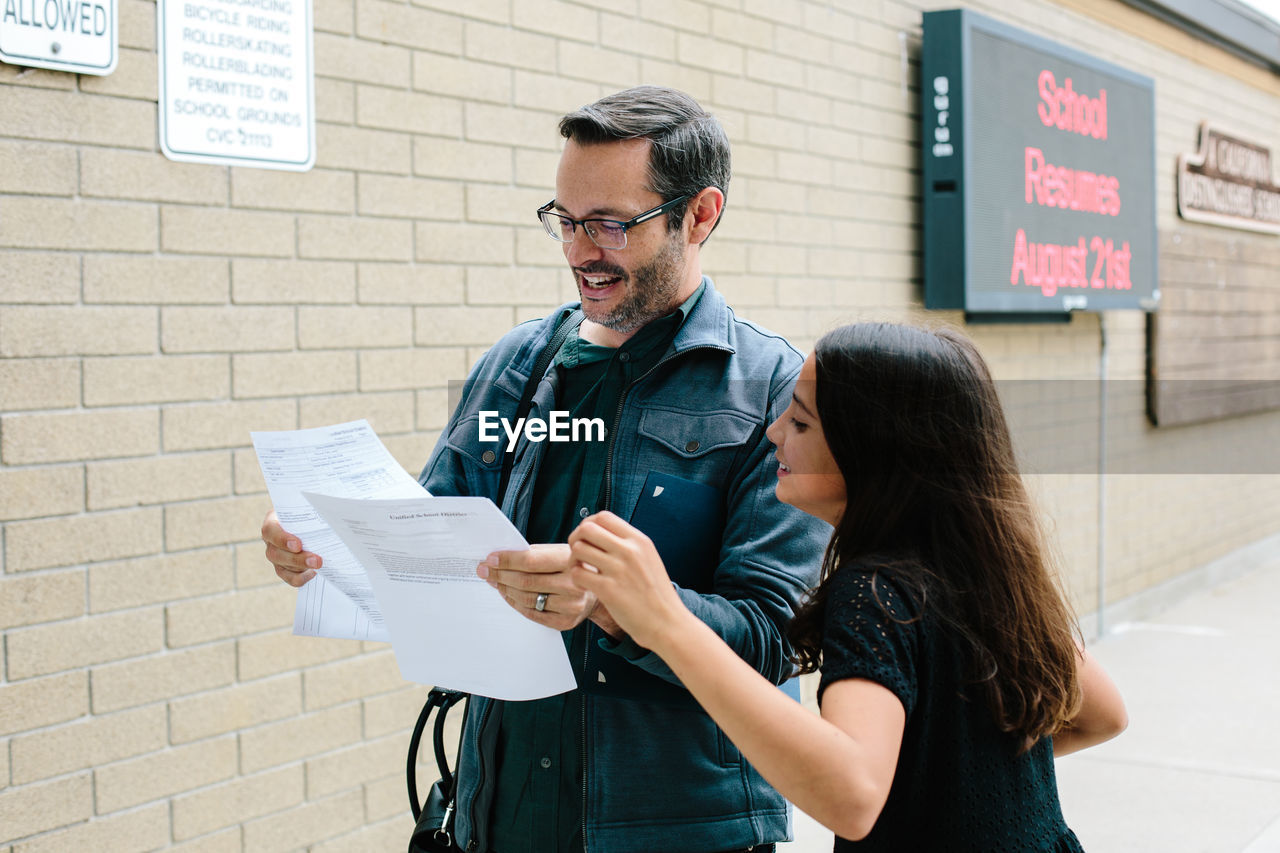 Father and daughter smile while looking at report card together