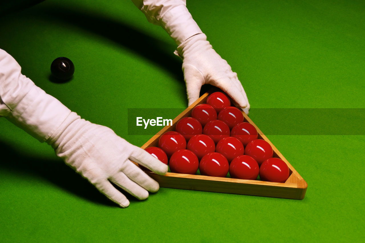 Cropped image of hands arranging snooker balls on table