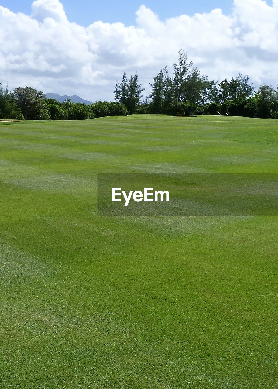 SCENIC VIEW OF GOLF COURSE AGAINST CLOUDY SKY