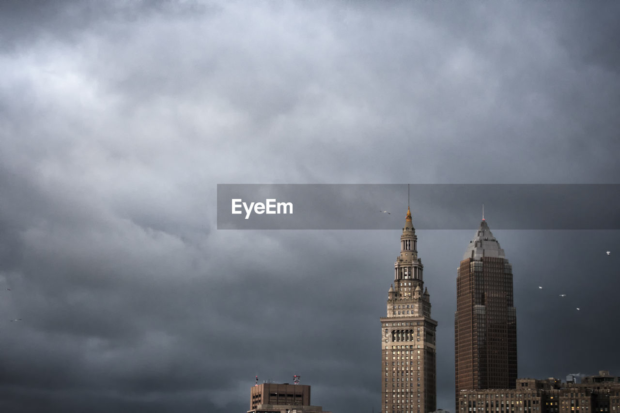 Low angle view of skyscrapers against cloudy sky