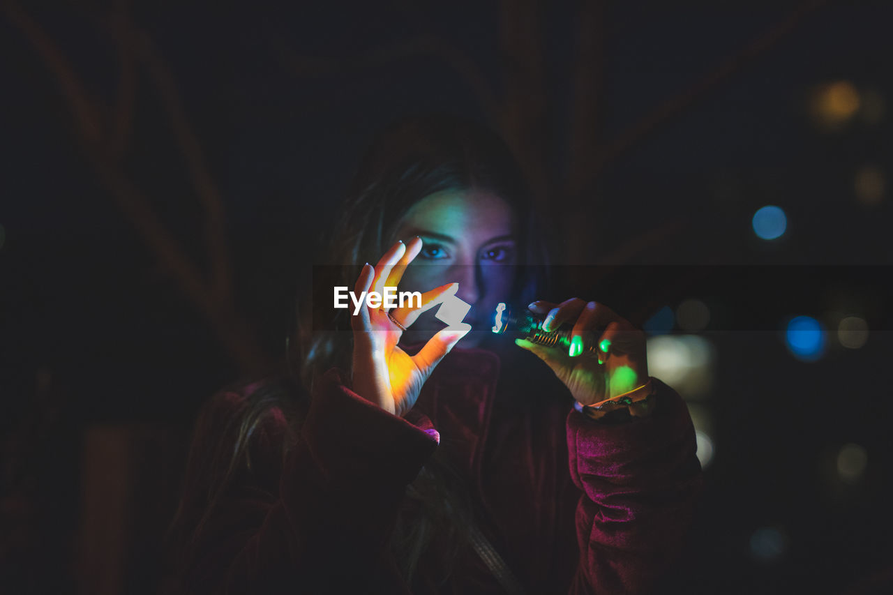 PORTRAIT OF YOUNG WOMAN LOOKING AWAY AT ILLUMINATED UNDERGROUND LIGHTS