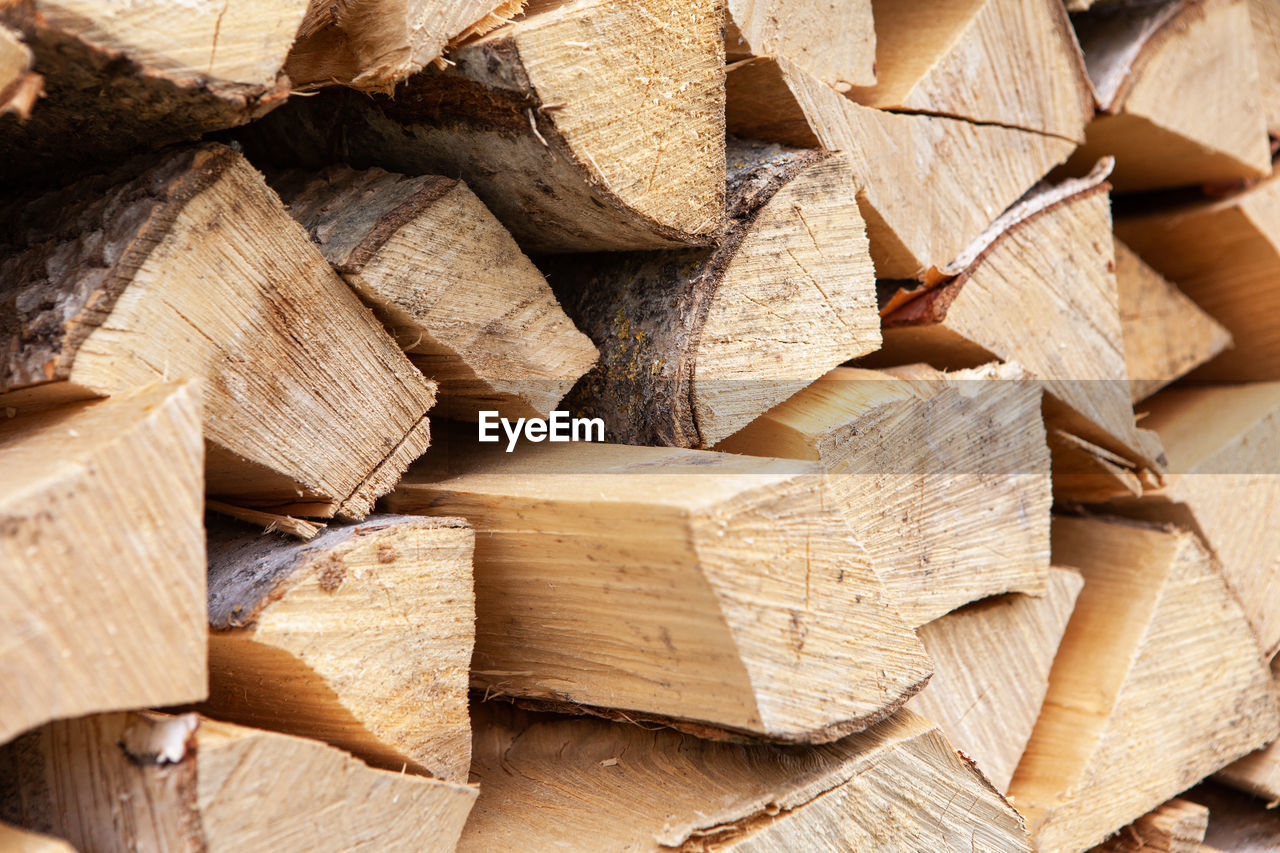 Background from stack of firewood from birch tree, for heating house, stacked in backyard, uncut