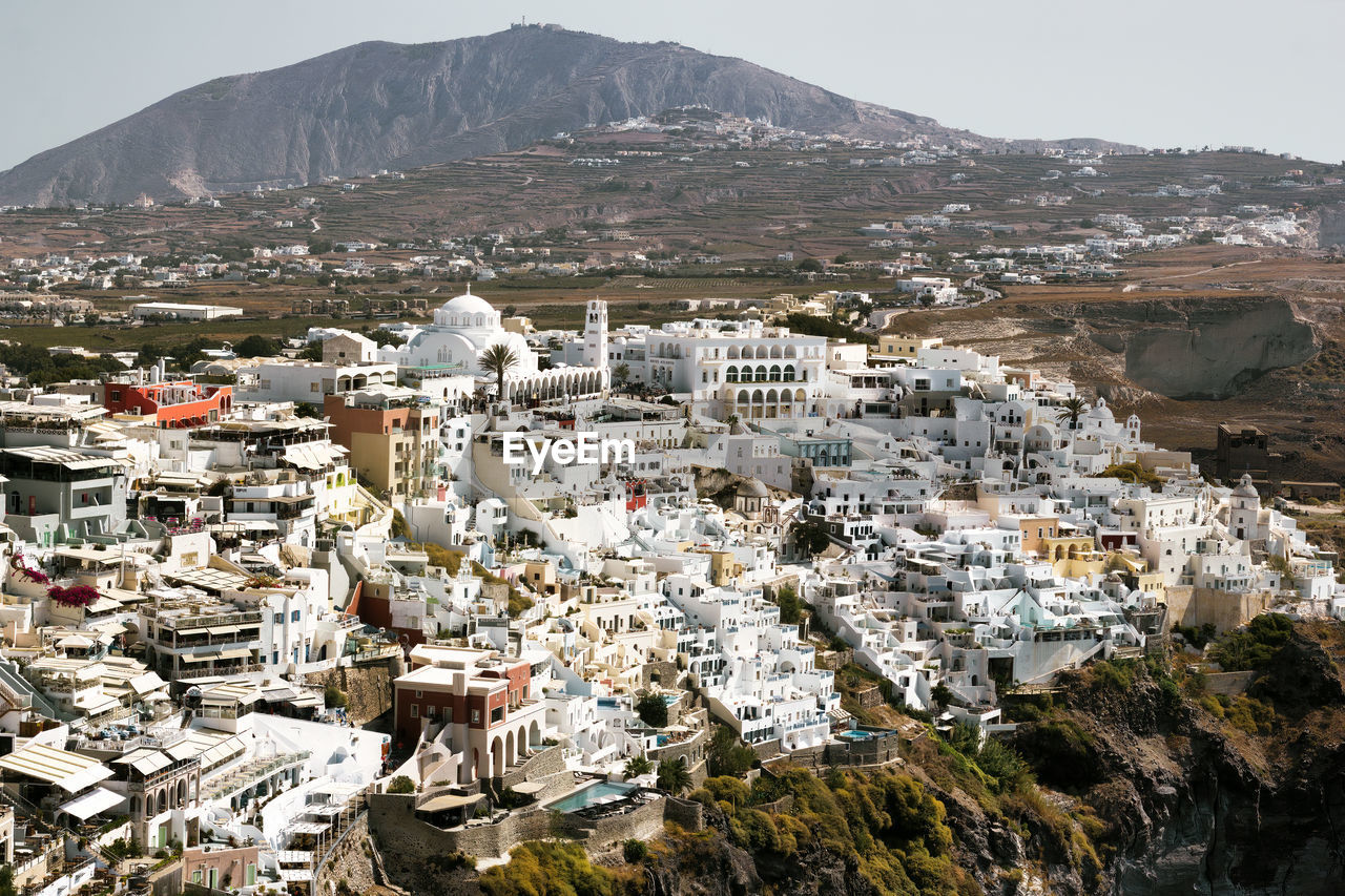 Drone aerial shot of thira village in santorini, oia located in greece against mountains. 